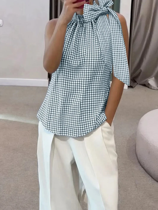Woman wearing a sleeveless gingham tie-neck blouse with white wide-leg pants