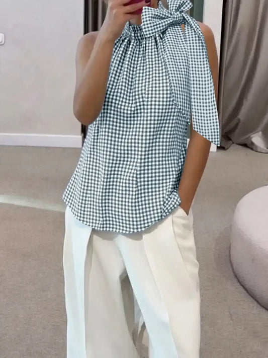 Woman wearing a sleeveless gingham tie-neck blouse with white wide-leg pants