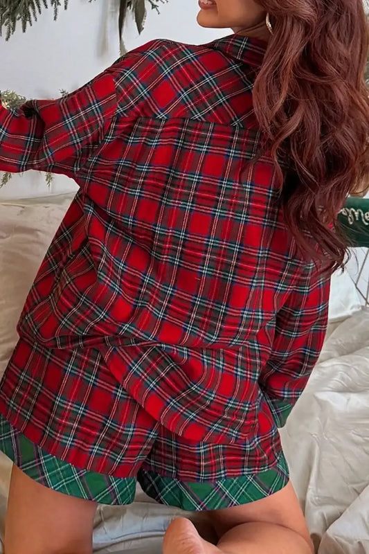 Woman wearing red and green plaid pajamas sitting on bed with long wavy hair and gold hoop earrings
