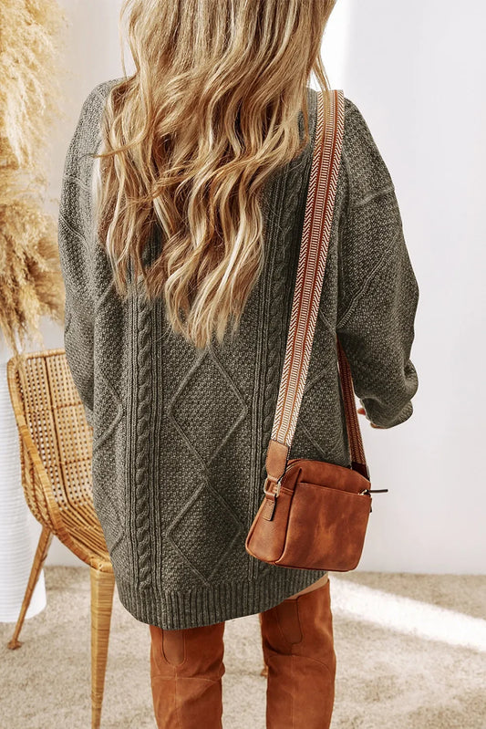 Woman wearing oversized gray knit sweater and brown crossbody bag with patterned strap