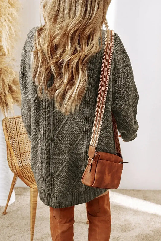 Woman wearing oversized gray knit sweater and brown crossbody bag with patterned strap