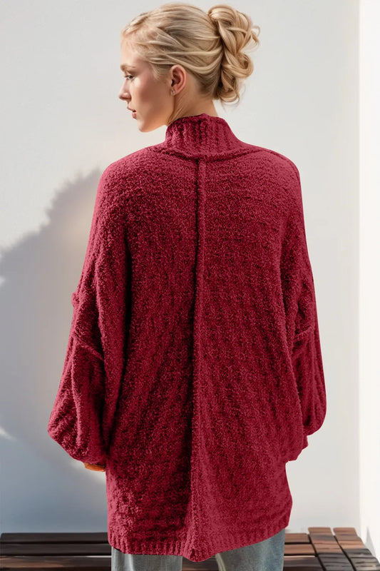 Woman wearing a cozy textured maroon oversized cardigan with high collar, back view