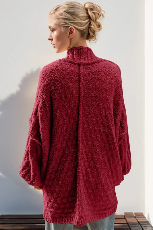 Woman wearing a cozy textured maroon oversized cardigan with high collar, back view