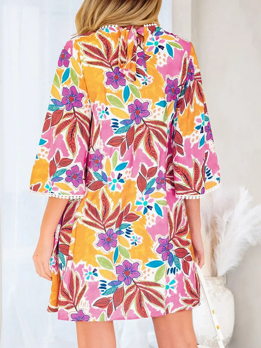 Woman wearing colorful floral print dress with bell sleeves and tie-back detail