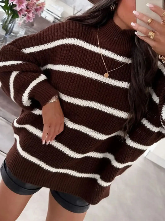 Woman wearing an oversized brown and white striped knit sweater and black leather shorts.