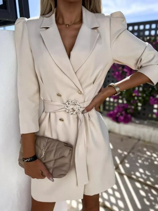 Woman wearing beige belted blazer dress with puff sleeves and holding beige quilted YSL handbag