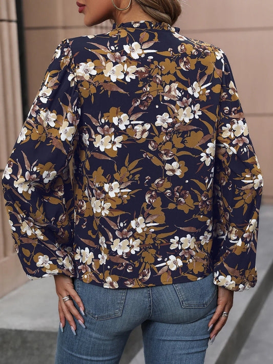 Woman wearing navy floral long sleeve blouse and blue denim jeans with gold hoop earrings