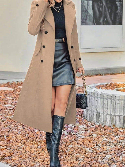 Woman wearing a long tan coat, black turtleneck, leather mini skirt, and knee-high boots.