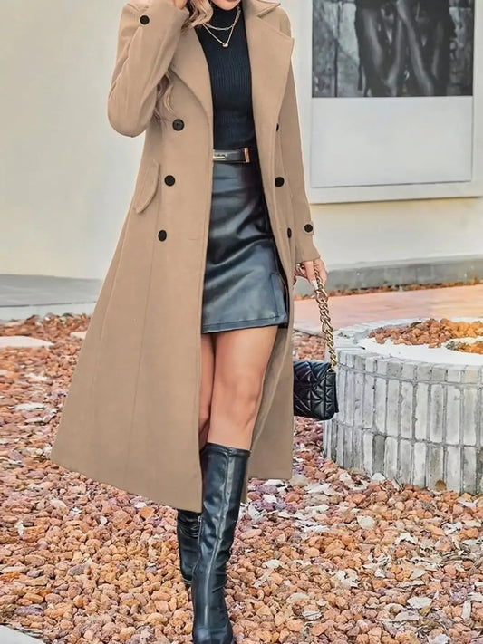 Woman wearing a long tan coat, black turtleneck, leather mini skirt, and knee-high boots.
