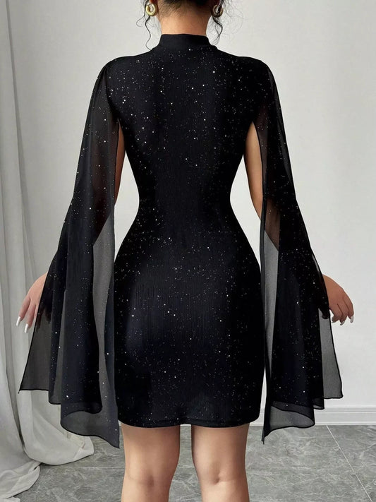 Back view of woman wearing a black glitter mini dress with flowy long sheer sleeves and gold hoop earrings