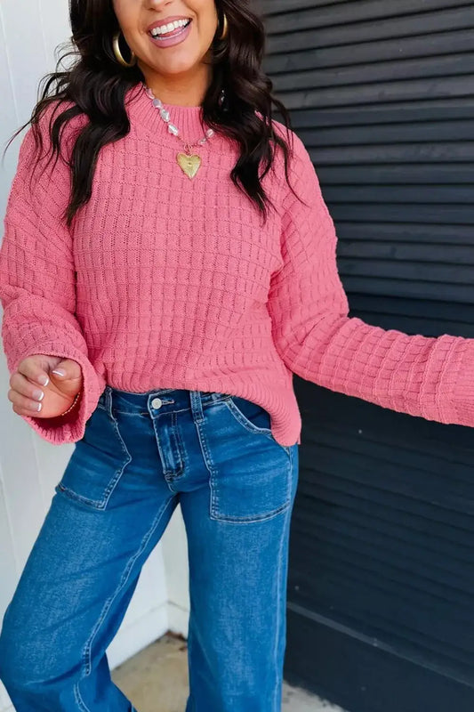Woman wearing a pink drop shoulder knit sweater with long sleeves and blue jeans by Evie's Dreamland.