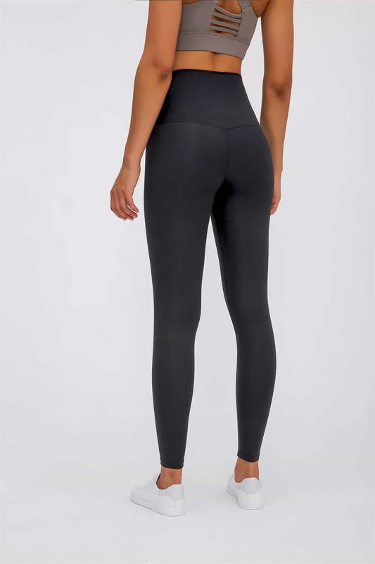Woman wearing black high-waisted leggings and gray sports bra with white sneakers
