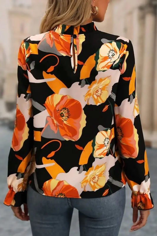 Back of woman wearing black blouse with large orange and yellow floral print and blue jeans