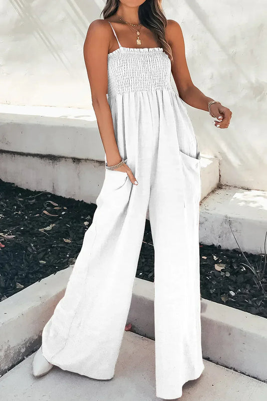 Woman wearing white wide-leg jumpsuit with smocked bodice and spaghetti straps outdoors