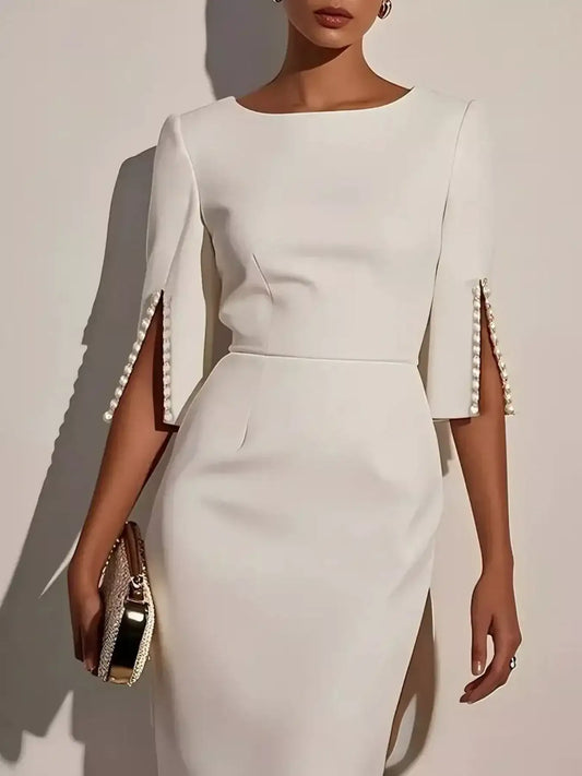 Woman wearing a white midi dress with pearl-embellished split sleeves and gold clutch