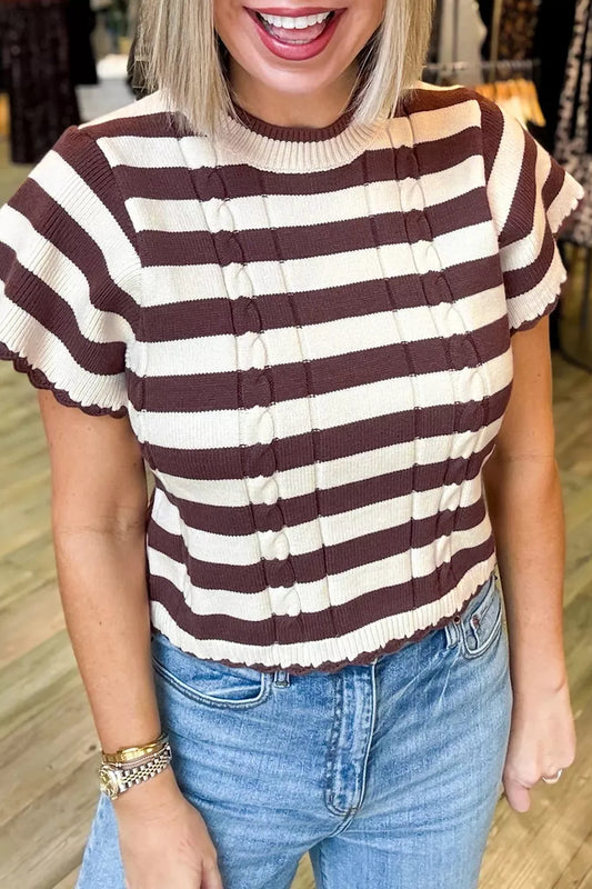 Woman wearing a brown and cream striped ribbed cable-knit short sleeve sweater paired with blue jeans.