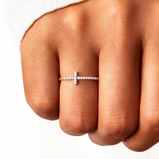 Evie's Dreamland rose gold 925 sterling silver cross ring with sparkling crystals on a woman's finger.