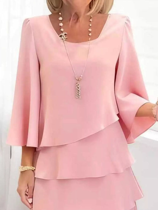 Elegant pink ruffled dress with bell sleeves and layered design, styled with chic necklace and bracelet.