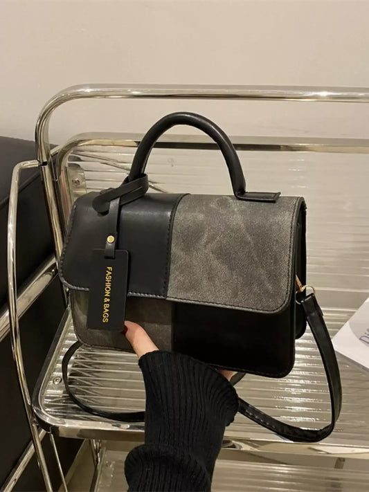 Two-tone black and grey women's handbag with top handle and shoulder strap.