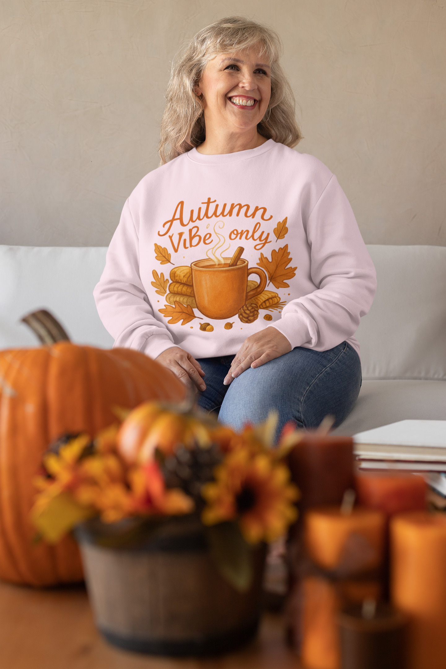 Woman wearing a 'Autumn Vibe only' sweatshirt with pumpkins and fall decorations in the background.