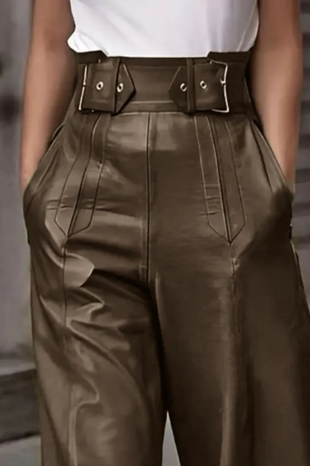 Close-up of high-waisted brown leather pants with wide belt and side pockets, styled with white top