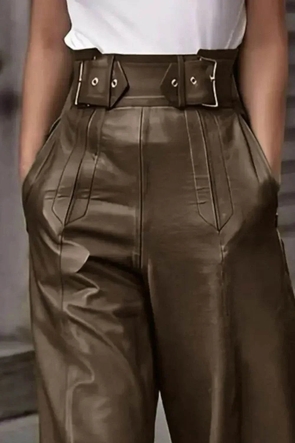 Close-up of high-waisted brown leather pants with wide belt and side pockets, styled with white top