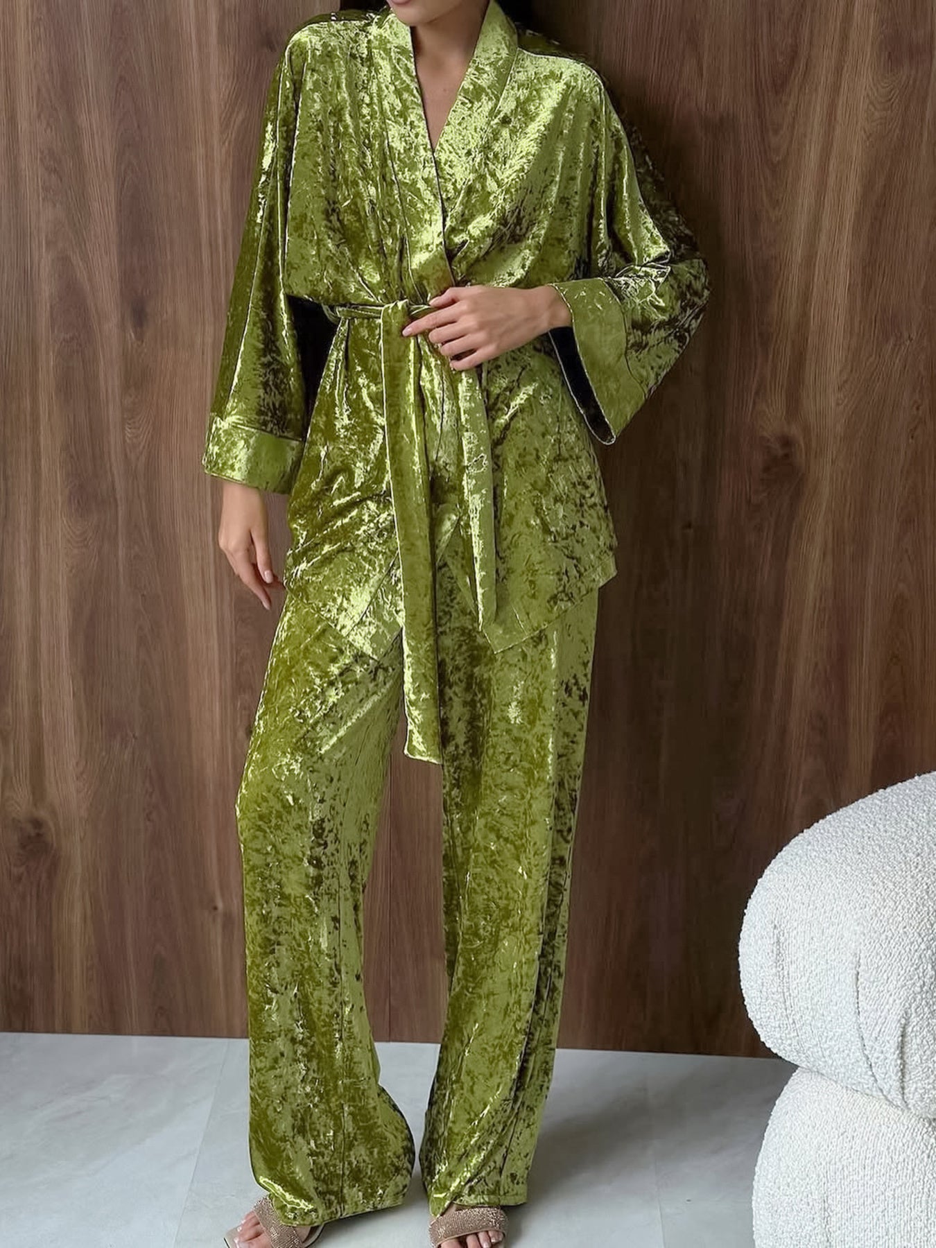 Woman wearing green velvet loungewear set with belted wrap top and wide-leg pants