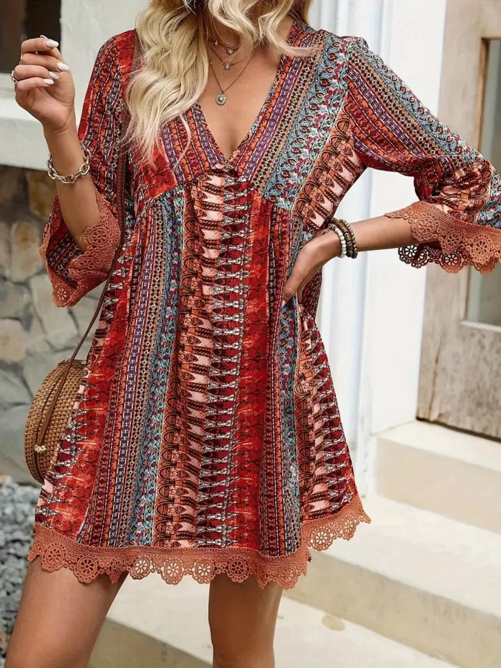 Woman wearing a boho chic red patterned mini dress with lace trim and three-quarter sleeves