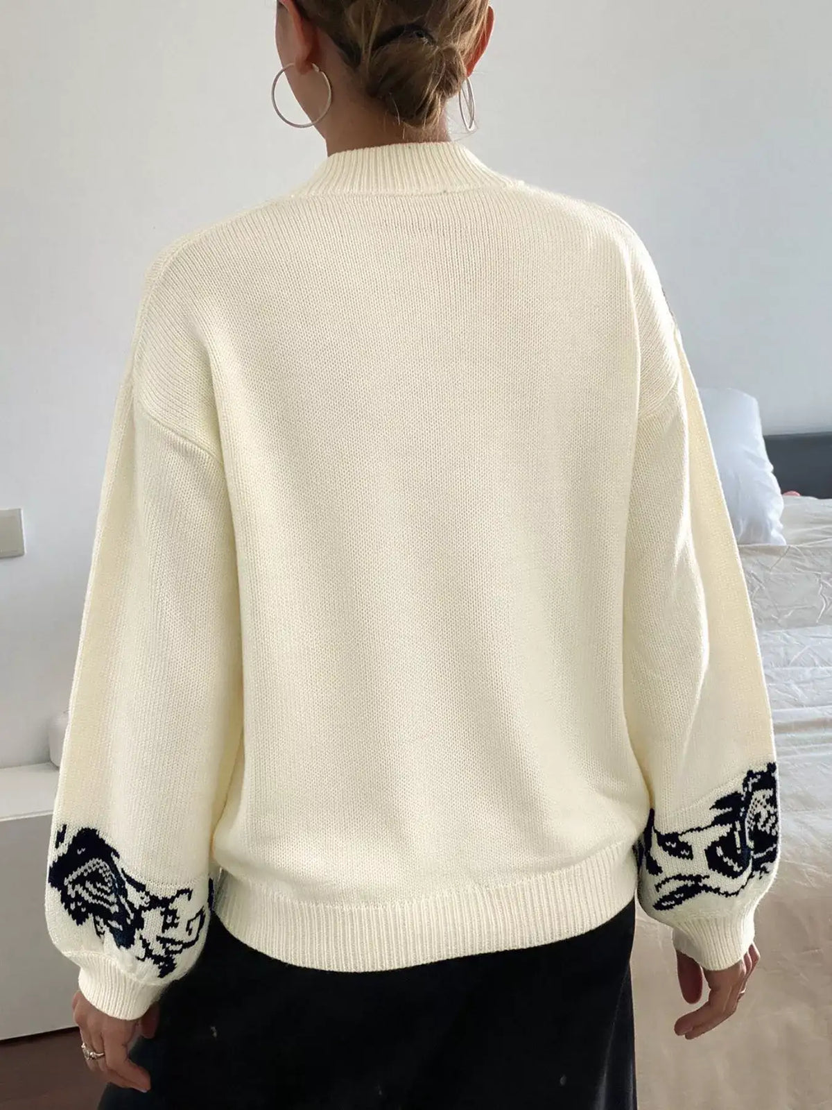 Back view of a cream Evie's Dreamland dropped shoulder sweater with black floral embroidery on the cuffs.