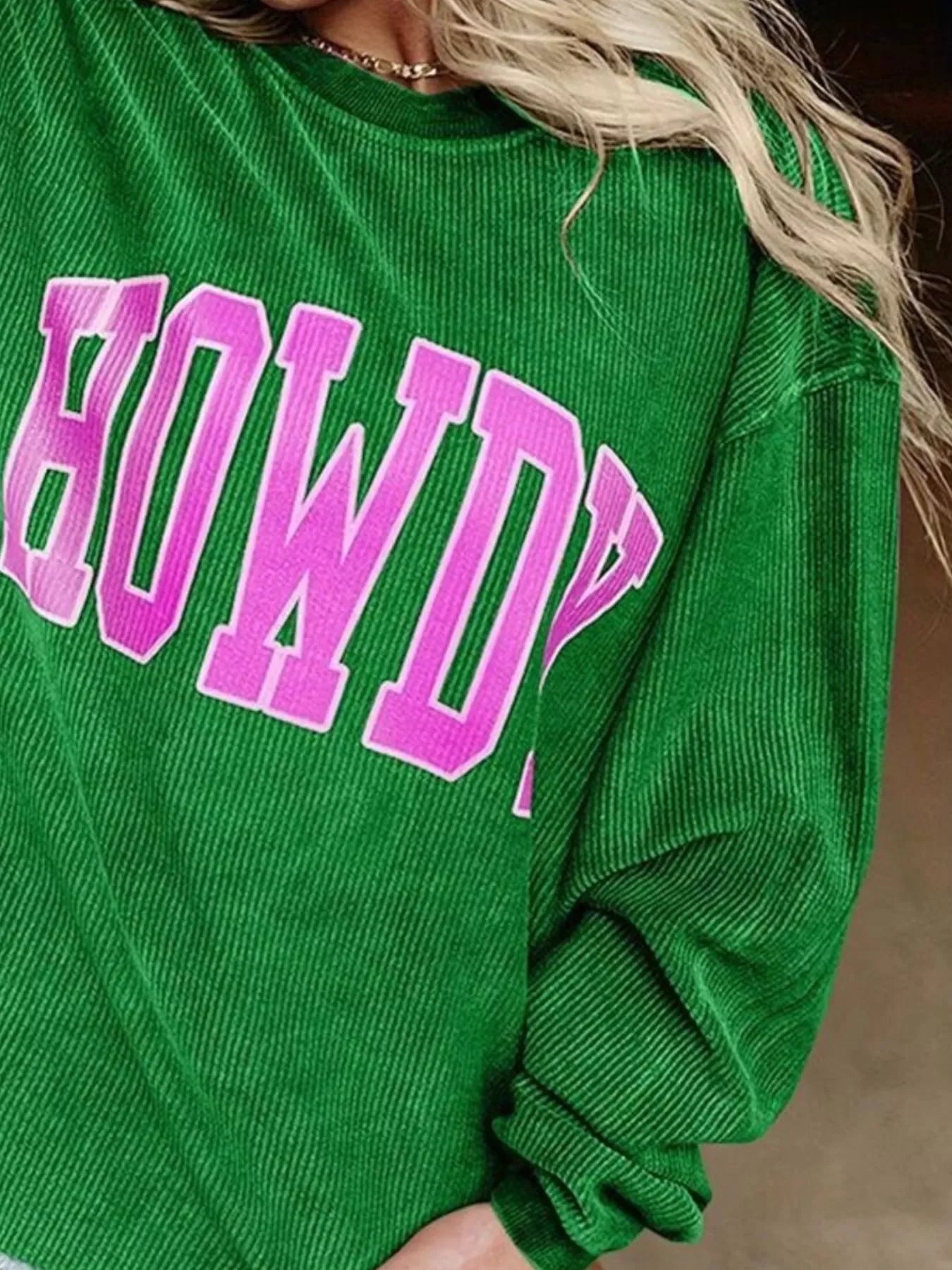 Green corduroy sweatshirt with pink block letters spelling HOWDY on the front