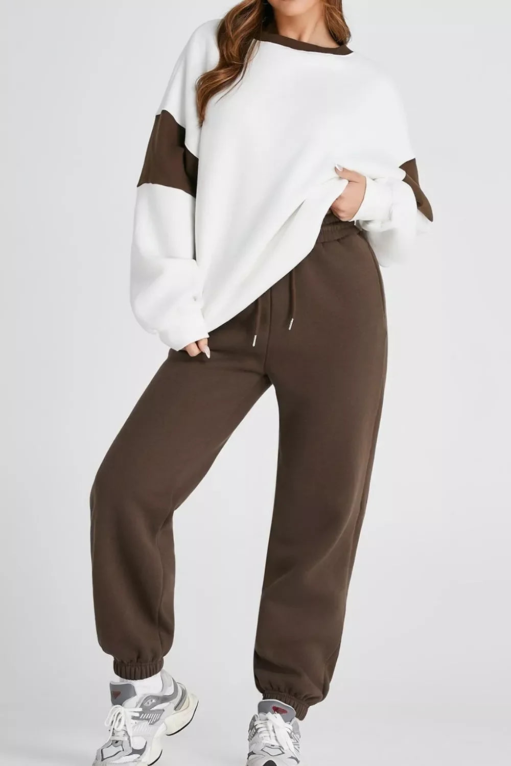 woman wearing white oversized sweatshirt with brown accents and brown jogger pants with sneakers
