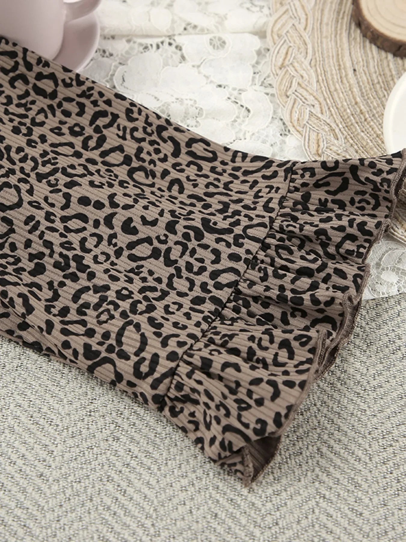 Brown leopard print pleated fabric with ruffle detail on a textured surface
