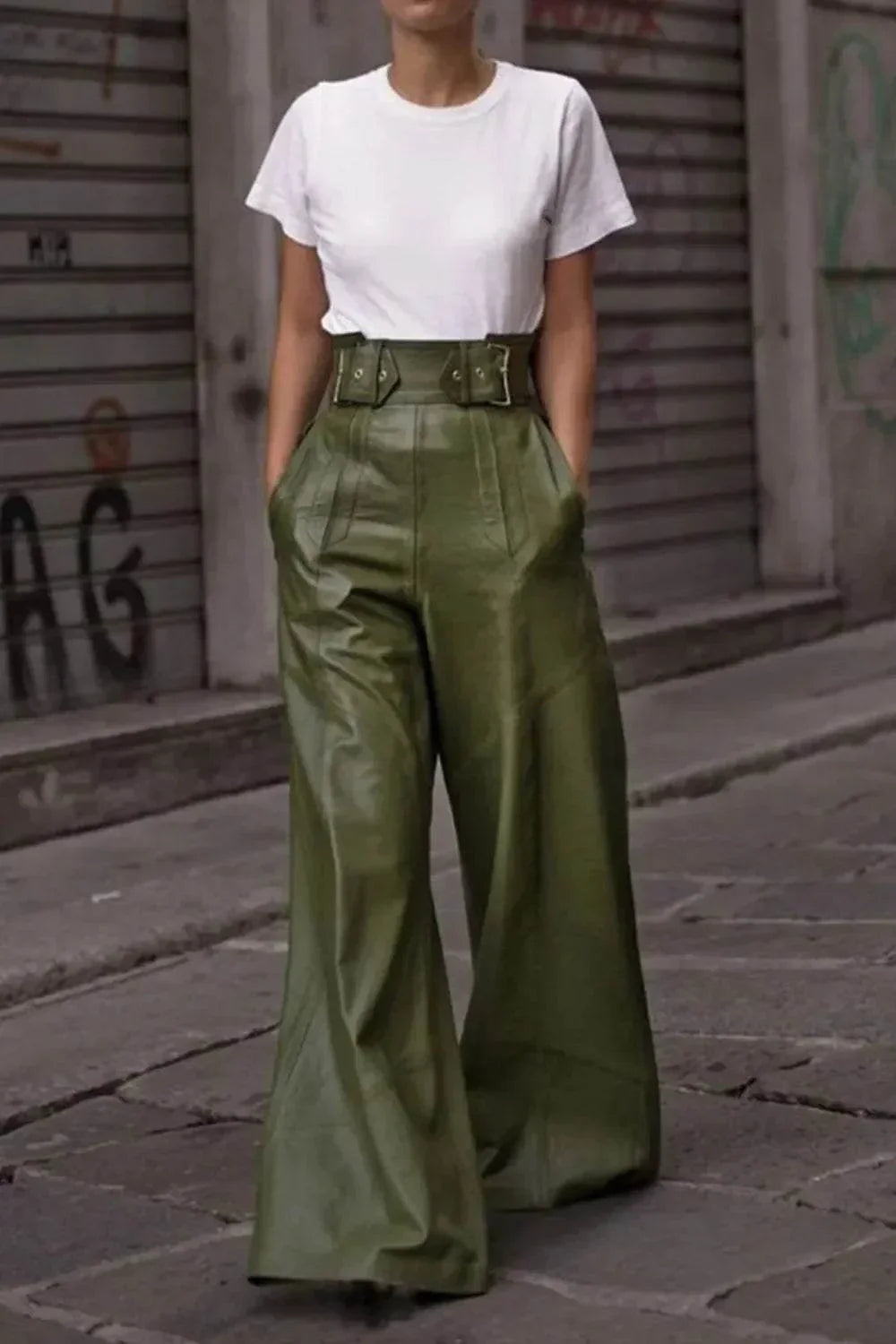 Woman wearing high-waisted olive green wide-leg leather pants and a white t-shirt on urban street