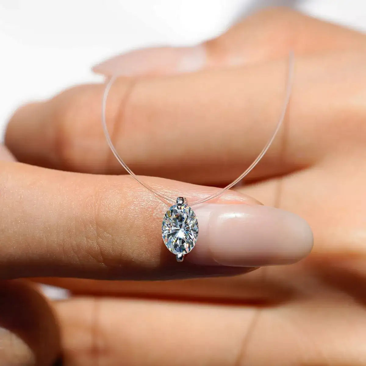 Close-up of a Moissanite oval pendant necklace by Evie's Dreamland held in a hand.