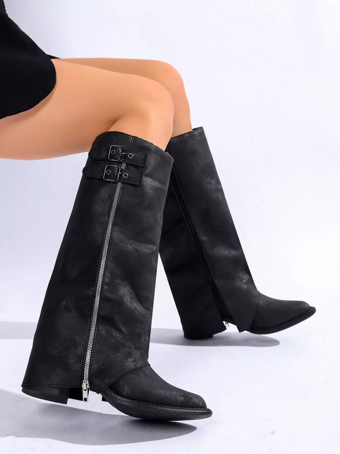 Woman wearing black faux leather mid-calf boots with side zippers and buckle details