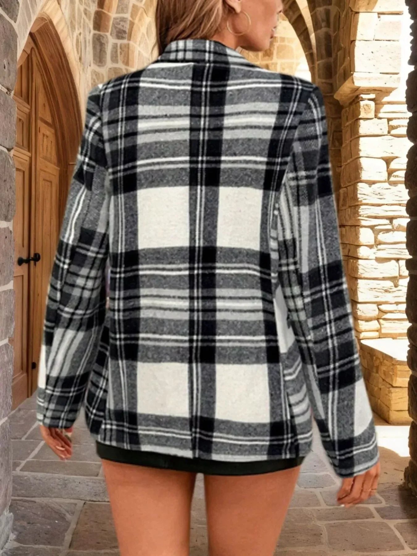 Woman wearing a grey, white, and black plaid oversized blazer from the back.
