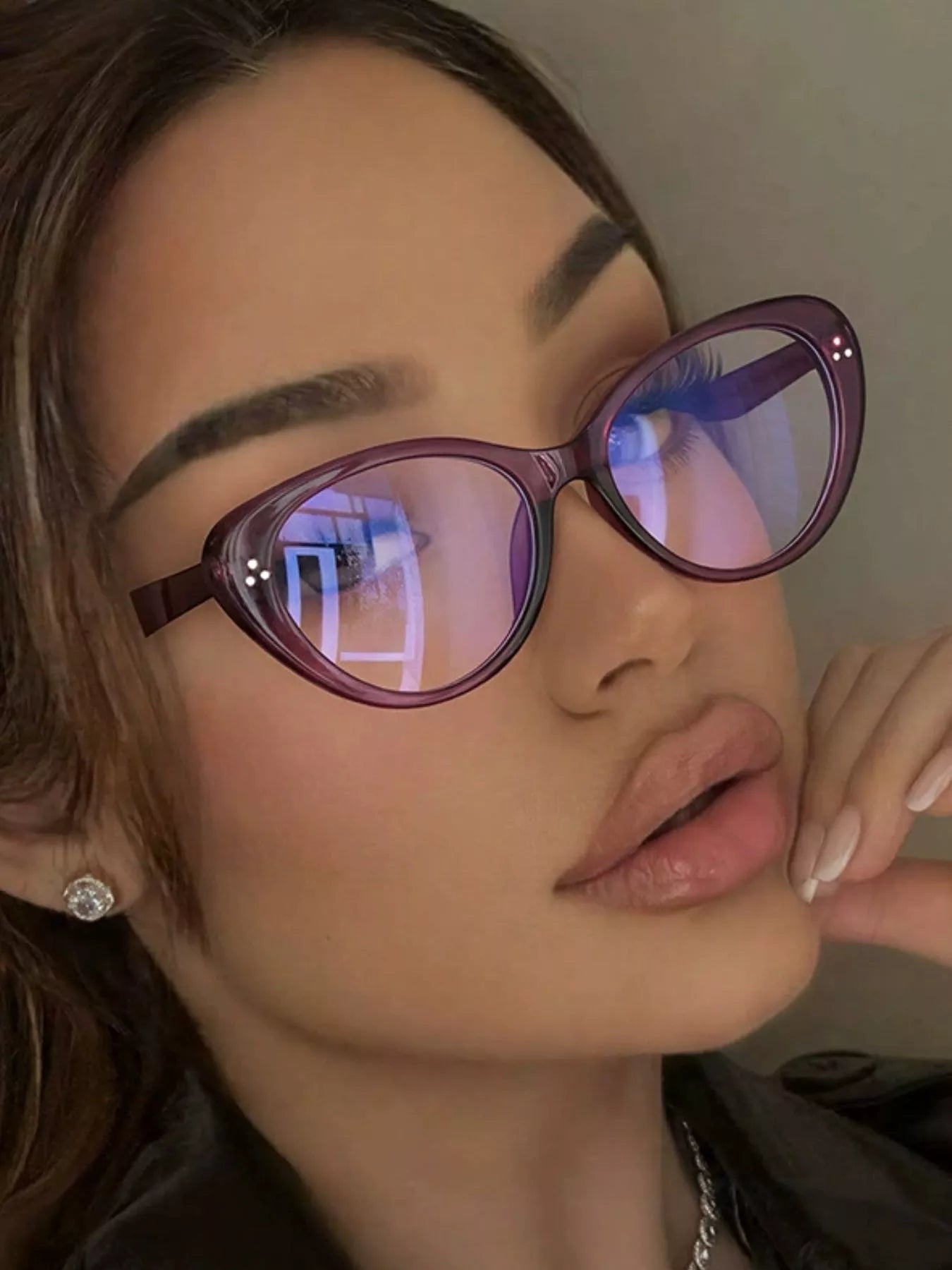 Woman wearing purple cat-eye blue light blocking glasses with silver earrings