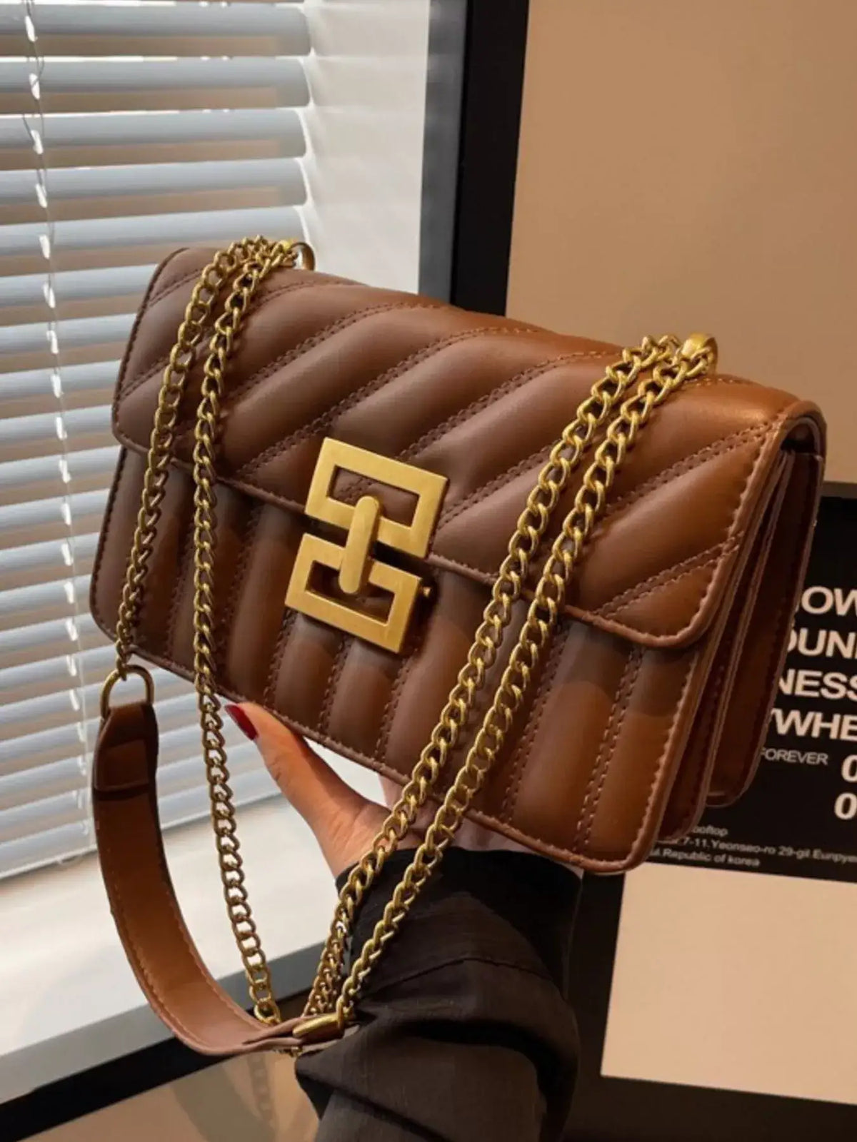 Brown quilted flap shoulder bag by Evie's Dreamland with a gold buckle and chain strap.
