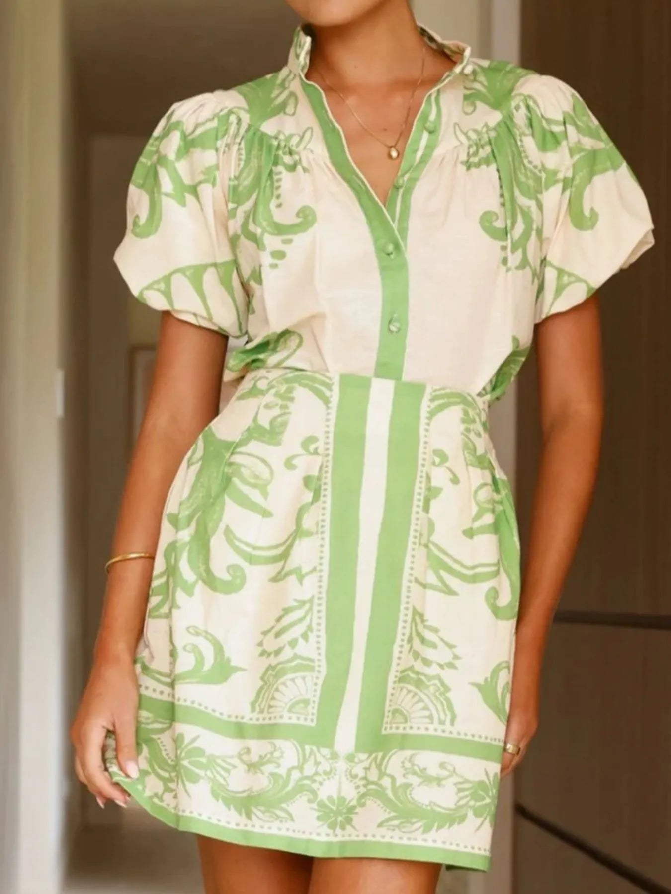 Woman wearing a green and cream puff sleeve mini dress with floral patterns, stylish summer outfit