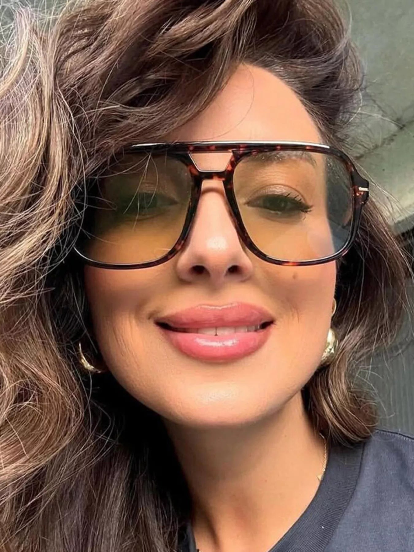 Woman wearing oversized tortoise shell sunglasses with yellow tinted lenses.
