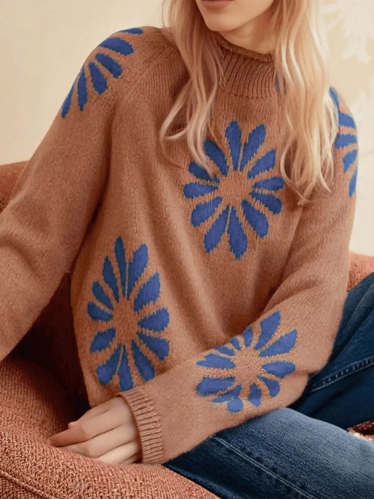 Woman wearing an Evie's Dreamland brown mock neck raglan sweater with blue floral patterns and blue jeans.
