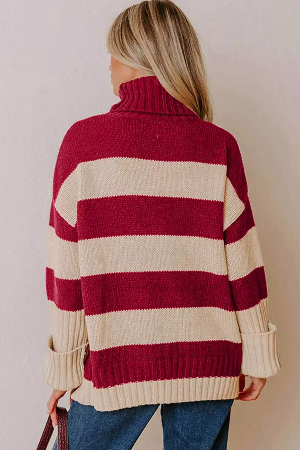Back view of a woman wearing an Evie's Dreamland red and beige striped turtleneck sweater with long sleeves.