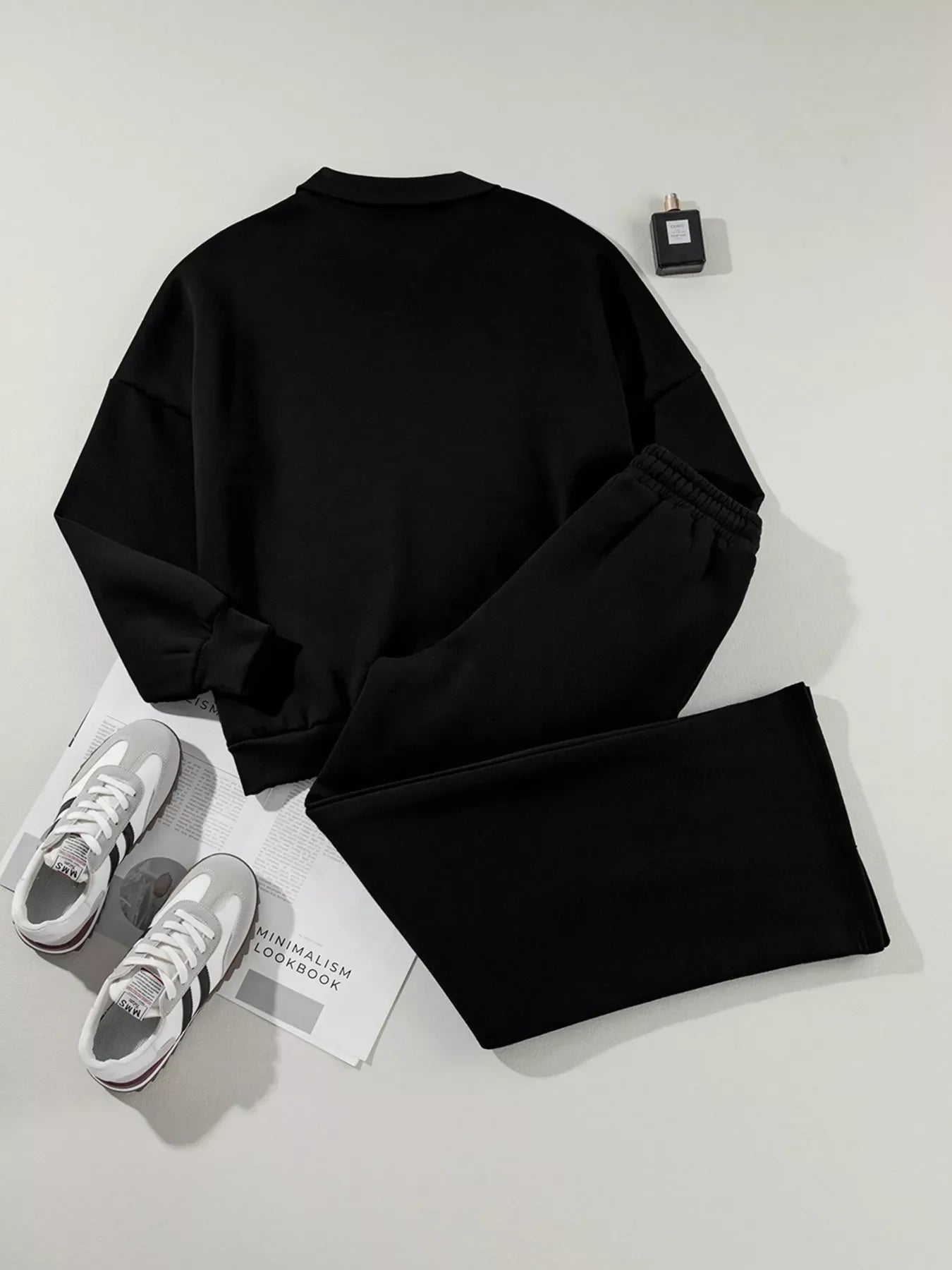 Black sweatshirt and pants set with white sneakers and minimalist lookbook on white surface