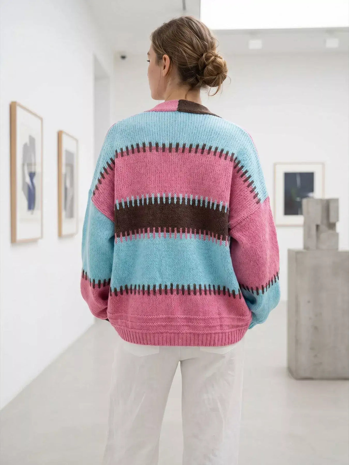 Back view of an Evie's Dreamland color-block v-neck cardigan in blue, pink, and brown with white pants.