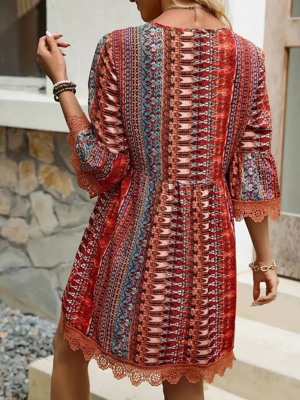 Woman wearing a red boho print dress with lace trim and 3/4 sleeves outdoors