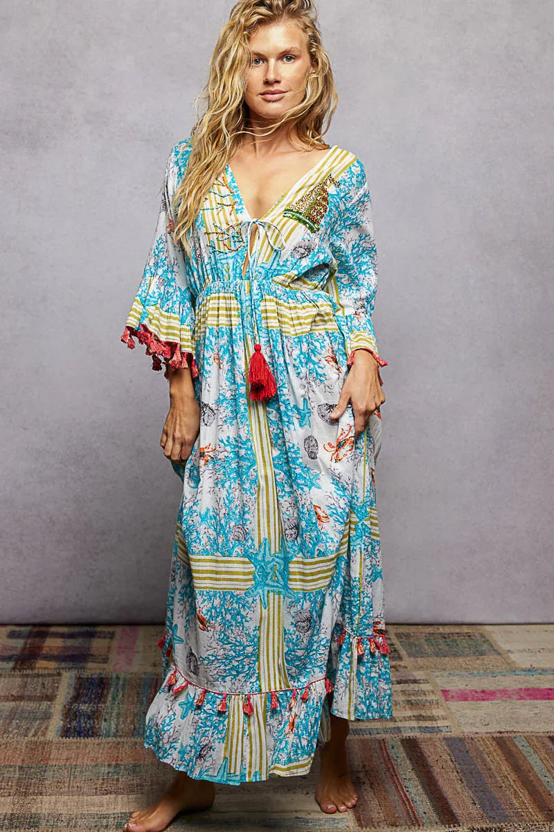 Woman wearing a colorful boho maxi dress with blue, yellow, and red coral reef print