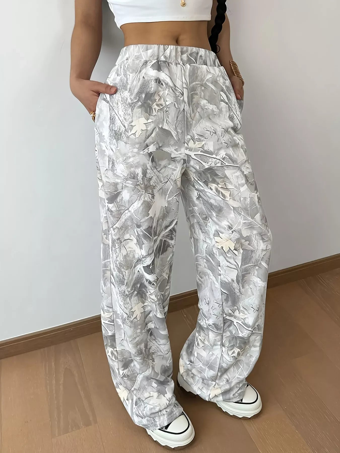 Woman wearing white and gray abstract printed wide-leg pants with pockets and white sneakers