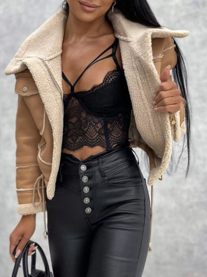 Woman wearing tan shearling jacket, black lace crop top, and high-waisted black leather pants with silver buttons