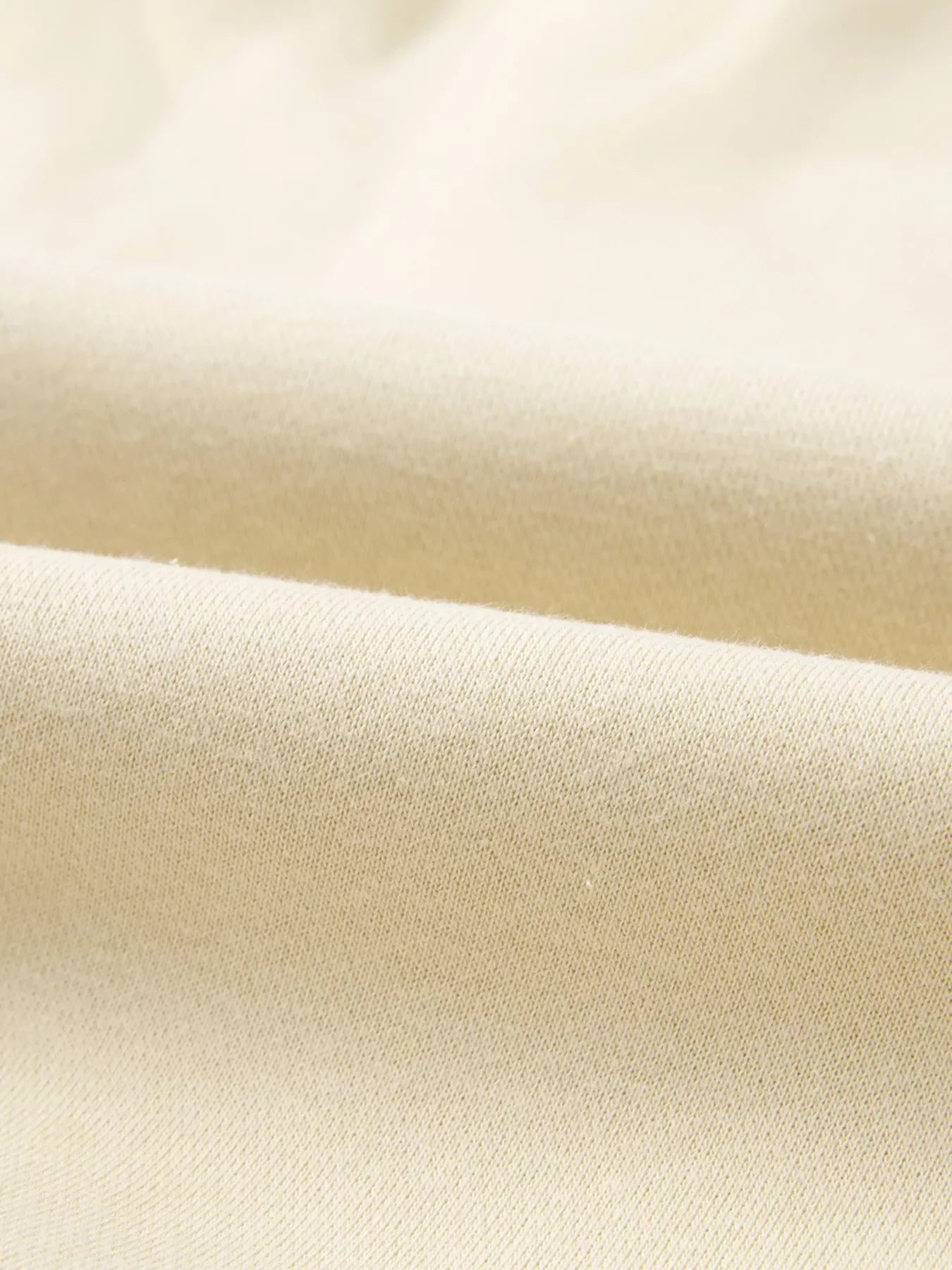 Close-up of soft cream beige fabric texture with gentle folds