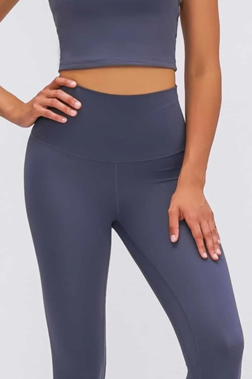 Woman wearing high-waist navy blue leggings and matching sports crop top on white background